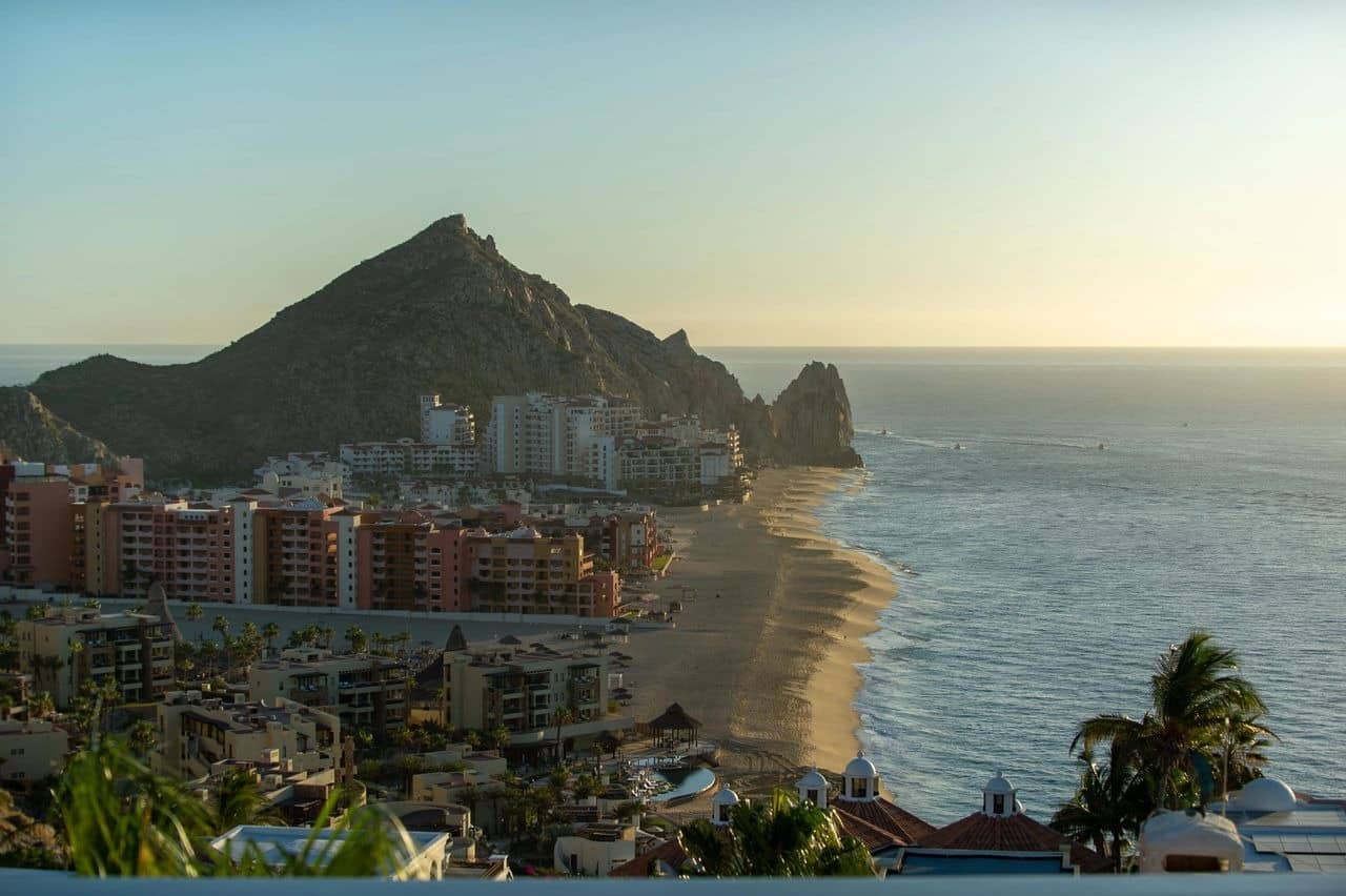 Sunset over coastal city with beach and mountain.